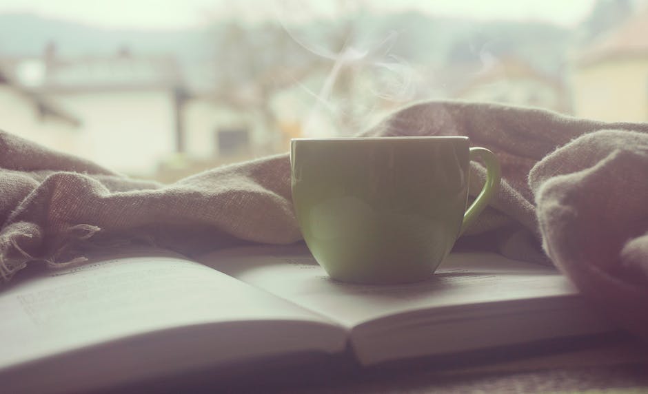 steaming cup of coffee sitting ontop of an open book